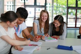 Jugendliche am Tisch. Foto: Kinder mit Lehrer. Foto: Christian Schwier / Adobe Stock