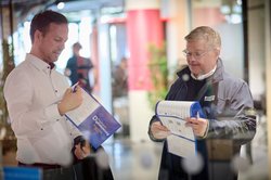 Besucher beim Praxisforum lesen den Programmflyer. Foto: Foto und Bilderwerk