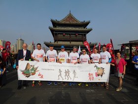 Die Oldenburger Laufdelegation steht vor einer Pagode. In der Hand ein Banner mit Motiven aus Oldenburg und Xi'an und der Aufschrift „Laufen verbindet“. Foto: Stadt Oldenburg