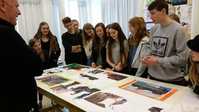Schülerinnen und Schüler stehen um einen Tisch herum, auf dem verschiedene Stadtansichten liegen. Foto: Anja Czibulinski
