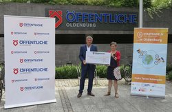 Christian Bunk, Vertriebsdirektor Öffentliche Versicherungen Oldenburg überreicht den Scheck für das Erreichen des vierten Etappenziels an Dr. Pia Winter, Geschäftsführerin der Elterninitiative krebskranker Kinder Oldenburg e.V. Foto: Stadt Oldenburg