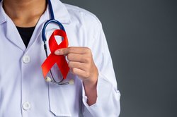 Ein Arzt hält eine rote Aids-Schleife in der Hand. Foto: jcomp/freepik.com