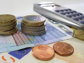 Geld und Taschenrechner liegen auf einem Tisch.
