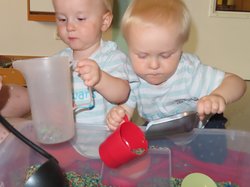 Zwei Kleinkinder spielen mit farbigem Reis. Foto: Stadt Oldenburg