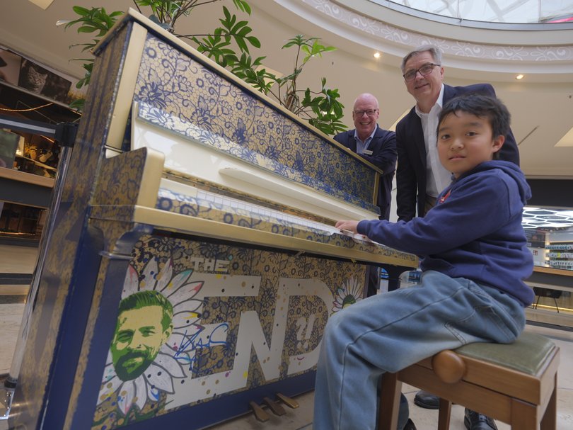 Der elfjährige Dominic Chen spielte als Erster auf dem Piano in den Schlosshöfen. Oberbürgermeister Jürgen Krogmann und Center-Manager Stefan Tenk (links) waren begeistert. Konterfei und Unterschrift von Klaas Heufer-Umlauf zieren das Instrument. Foto: Sascha Stüber 