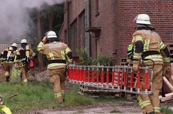 Zwei Kameraden der Feuerwehr tragen eine Leiter zu einem brennenden Haus. Foto: Feuerwehr Oldenburg