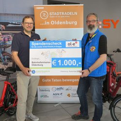 Michael Ottens, Inhaber ol-e urban:mobil, überreicht den Scheck für das Erreichen des zweiten Etappenziels an Stephan Mickoleit, Mitarbeiter Bahnhofsmission Oldenburg. Foto: Stadt Oldenburg