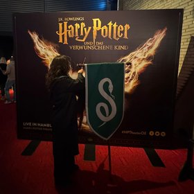 Eine Besucherin steht mit einem Zauberstab vor einem Harry Potter Werbeschild. Foto: Stadt Oldenburg