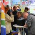 Vorschau: Menschen stehen fröhlich an einem Stehtisch. Foto: Robert Gertzen