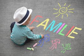Kind schreibt mit Kreide das Wort „Familie“. Foto: motorradcbr/Fotolia.com